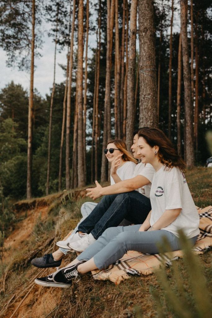 Two friends enjoy a peaceful day in the forest on a cozy blanket, surrounded by nature.