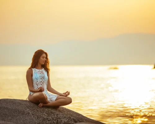 a woman meditating on the beach