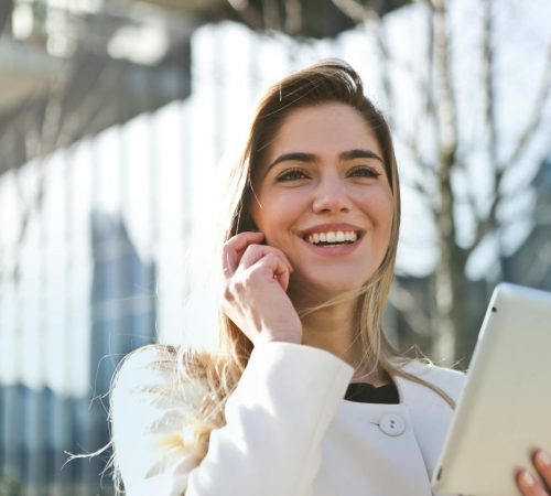 woman in white blazer holding tablet computer